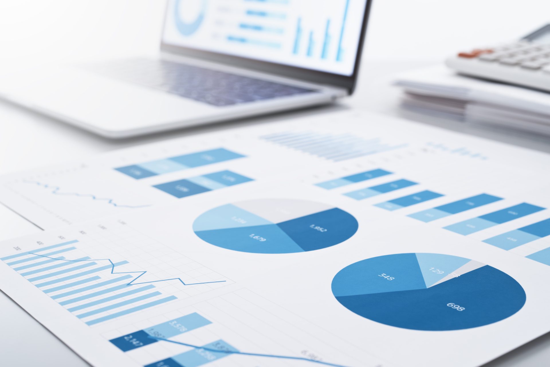 報告書とノートパソコンの画面に多数のグラフ。