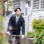 自転車に乗ったスーツ姿の若い男性