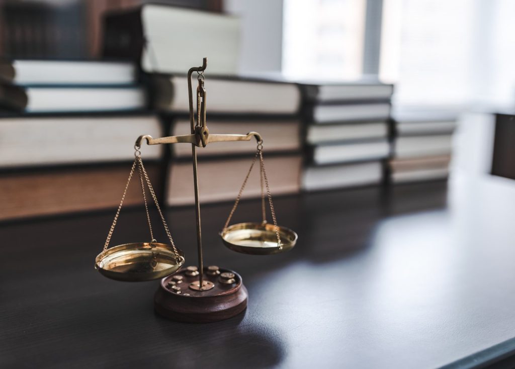 法令違反を招くリスクを示唆する天秤のイメージ