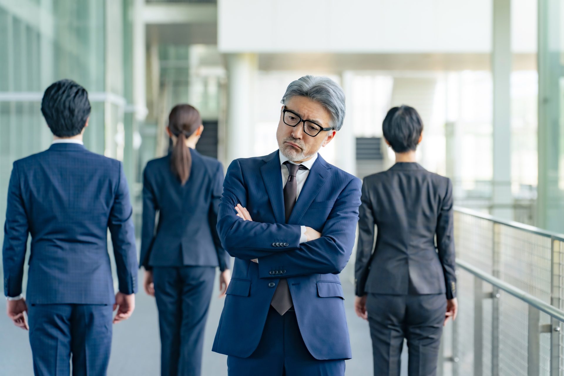部下に背を向けて悩むシニアのビジネスパーソン