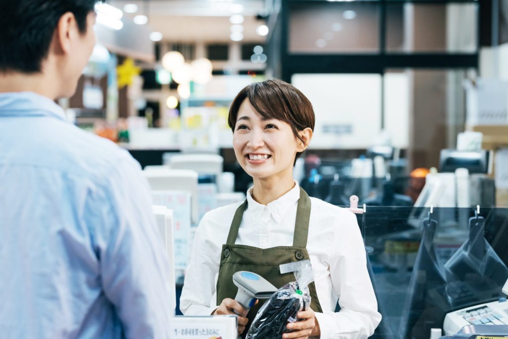 スーパーマーケットのレジで接客を行う店員のイメージ